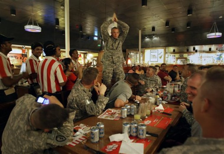 Sgt. Charles Reed, from Steam Boat, Colo., of the 715 Military Intelligence Unit, center, celebrates his 34th birthday with his colleagues and the staff at T.G.I. Fridays restaurant on the boardwalk at Kandahar Air Force Base, Afghanistan on Monday.